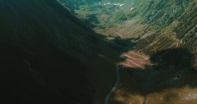 Beautiful landscape view with mountains, road serpantine from above through white light clouds.