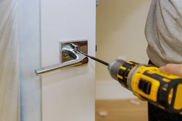 Carpenter installing door lock in the new house