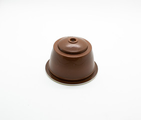 A single brown espresso coffee capsule isolated on white background.