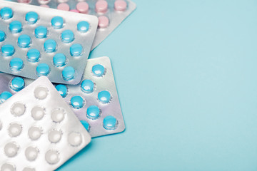Close up view of hormonal pills in blisters on blue surface