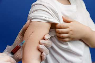 Doctor or nurse gives the boy an injection. Personal protective equipment against viruses and infections. Flu or coronavirus vaccine.