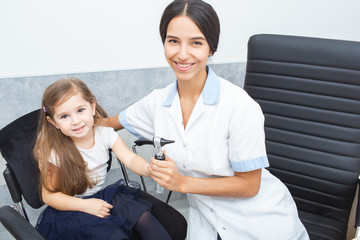 Fototapeta premium Audiologist doing joint photo with little girl patient at hearing clinic. Treatment of childhood deafness