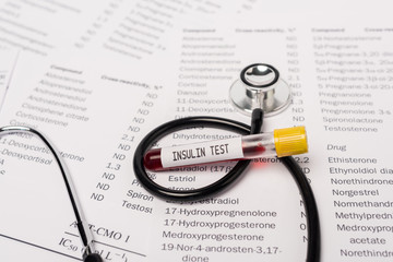 Close up view of stethoscope and test tube with insulin test lettering on lists with hormones