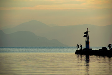 Fototapeta premium People are fishing during sunset time at the port of Aegina island.