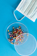 Mask and people on petri dish. High price concept for population infection of pandemic coronavirus covid-19. Concept to describe spred of virus and cost for public health system.