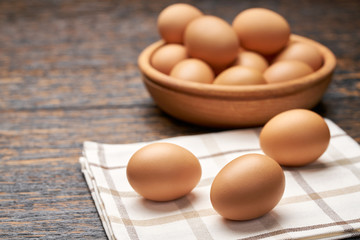 Сhicken eggs in a wooden bowl on a black wooden table, selective focus.