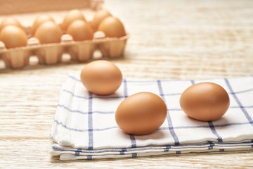 Organic  eggs in carton box on a white wooden table, selective focus.