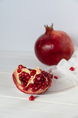 Whole fruit and halves of ripe pomegranate lie on a table on a wooden background. Organic Bio fruits