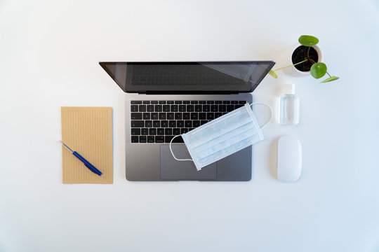 Top view of modern workspace during coronavirus quarantine, laptop, face mask, hand sanitizer, 