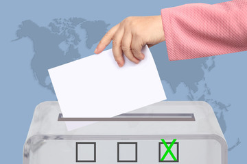 Voter’s female hand lowers the ballot in a transparent ballot box on the background, concept of...