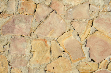 Light stone wall close-up. Brickwork of yellow, gray and orange stones and cement or concrete between them. Abstract urban backdrop. Copy space. Building background. Place for text.
Selective focus.