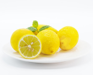 Fresh yellow lemons  with leaves on the white plate isolated on white background