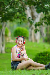 Asian young woman playing with french bulldog on green yard.