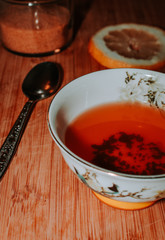 cup of red tea with lemon slice and a spoon with sugar on a wooden background