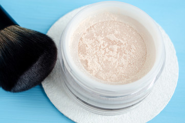 Loose face powder in the jar close up and make-up brush.
