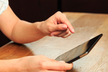 female hands holding tablet on wooden background .