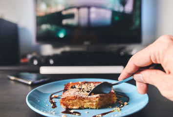 subjective first-person view of a hand holding a piece of almond cake on a coffee table with a blurred background
