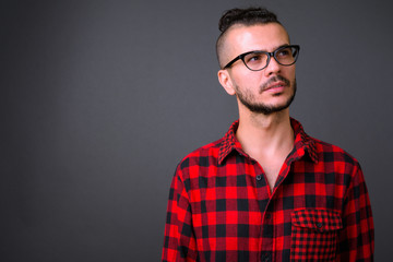 Face of handsome bearded Turkish hipster man with eyeglasses thinking