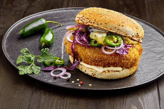 Sandwich made of chicken burger red onion, pickled cucumber, jalapeno and mayonnaise. Classic American cuisine.