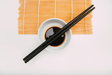 Stock photo of soy bowl with chopsticks on top on a cook mat and white background