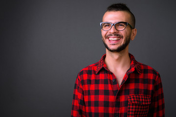 Face of happy bearded Turkish hipster man with eyeglasses thinking