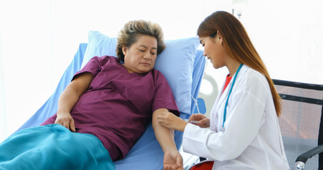 Obraz premium The doctor is using the syringe for the sick old woman lying on the bed