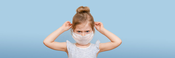 A little blonde girl in a protective medical mask. Gauze bandage on the face on a blue background. Banner.