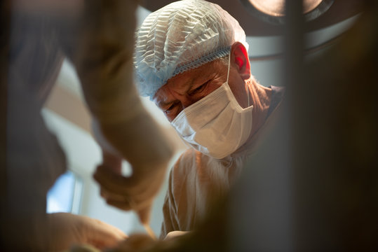 Kiev, Ukraine - 11 March 2016: Documentary During The Surgery At The Hospital. Concentrated Surgeon Doing Operation Under Operation Light