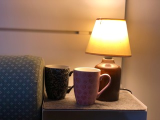 lamp and cup of coffee on the table next to sleeping bed