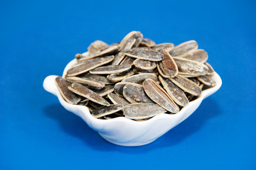 natural small sunflower seeds in a white plate on a blue background