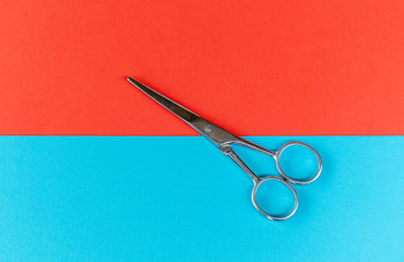 Scissors on blue and red color paper texture background.