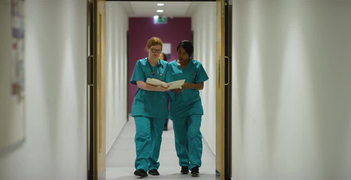 Two Medical Staff Walk Through Corridor