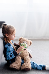 side view of kid holding respiratory mask near teddy bear