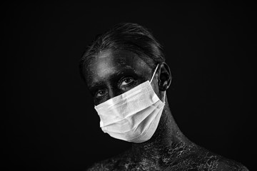 Coronavirus, masked woman. Studio portrait of a young woman wearing a face mask, looking at camera, on black background. Influenza epidemic, dust allergy, virus protection. City air pollution concept