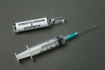 Syringe and ampoule with label Hydroxychloroquine and azithromycin. Gray background. Vaccine coronavirus