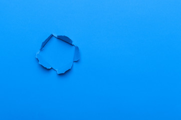 Blue color background with hole in the paper. Copy space.