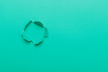 Green color background with hole in the paper. Copy space.