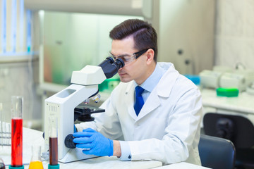 Scientist carries out scientific research looking through microscope in a medical laboratory....