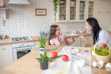 Brunette woman and her cute daughter spending time in the kitchen