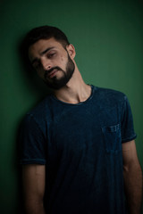 Portrait of young brunette Indian Kashmiri man in casual tee shirt in green copy space studio background. lifestyle and fashion.