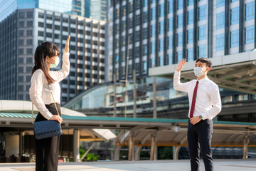 Asian business man and woman greet and say hello with business colleague and wearing mask standing...