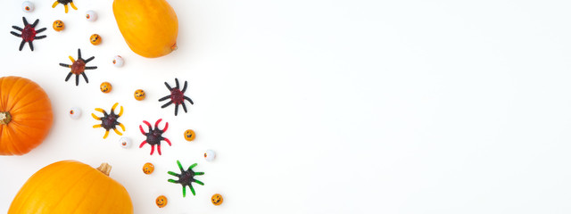 Obraz na płótnie Canvas Overhead Halloween Banner Composed Of Pumpkins With Candy Spiders And Eyeballs On White Background