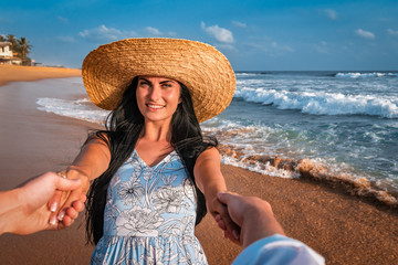 Fototapeta na wymiar girl holds her boyfried hands on the beach