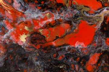 Red, black and gold paint liquid background. Abstract marble texture.