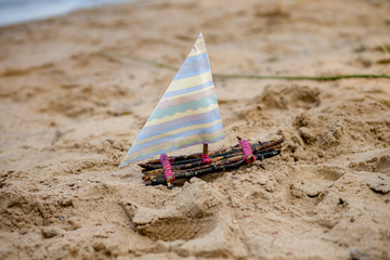 Fototapeta na wymiar One toy boat on sandy beach A toy sailing ship in the river