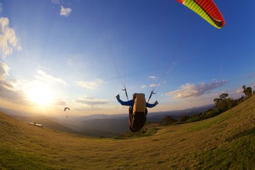 man flying a paraglider at sunset