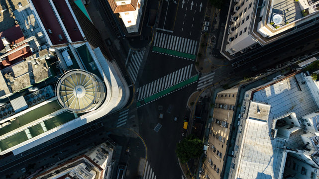 Aerial top down view on four way intersection in between tall buildings during golden hour (sunset time) with no people or traffic due to corona virus quarantine - 24 March 2020
