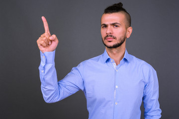 Portrait of handsome bearded Turkish businessman pointing up