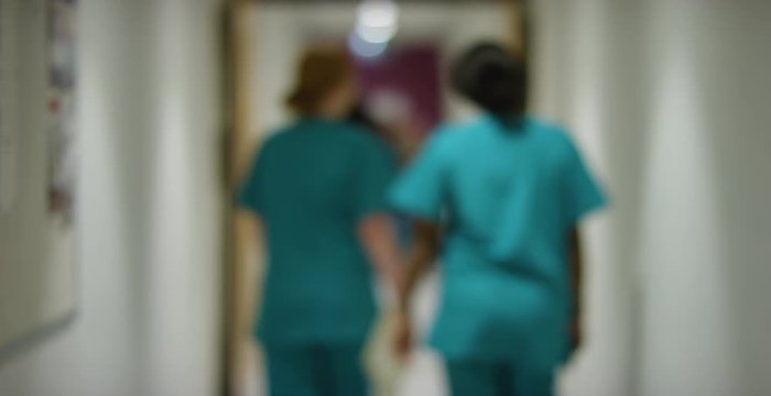 Blurred Medical Staff Walking Away  In Hospital Corridor