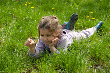 Fototapeta premium Sweet little girl take a rest on the grass in the garden